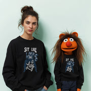 A woman wearing a black sweatshirt with a graphic of a raccoon and the text 