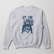 A gray sweatshirt with a graphic design featuring a raccoon sitting on a chair and the text 