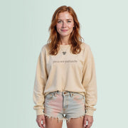 A young woman with red hair wearing a beige sweater with the text 