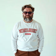 A man with a beard wearing a white long-sleeved shirt with the text 
