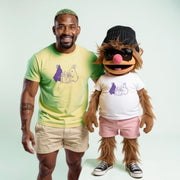 A man in a yellow t-shirt and khaki shorts stands next to a large, furry mascot wearing a white t-shirt and pink shorts.