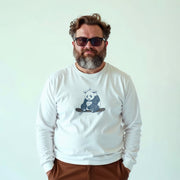A man with a beard wearing a white long-sleeved shirt with a graphic of a panda on a skateboard.