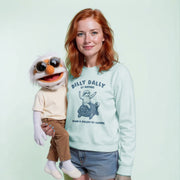 A woman with red hair is holding a large, white, cartoonish stuffed animal with sunglasses on its head. The stuffed animal appears to be a character from a children's television show or movie.