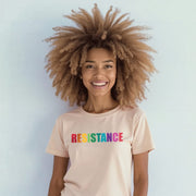 A smiling woman with curly hair wearing a white t-shirt with the word 