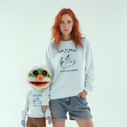 A woman with red hair wearing a white sweatshirt with a graphic and text, and a smaller character wearing a matching sweatshirt, standing together against a white background.