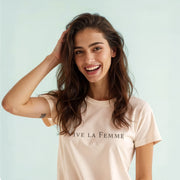 A smiling woman with long brown hair wearing a white t-shirt with the text 