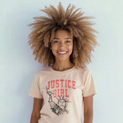 A smiling woman with curly hair wearing a t-shirt with the text 