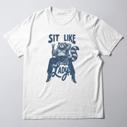 A white t-shirt with a graphic design featuring a raccoon sitting on a woman's lap and holding a drink.