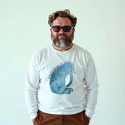 A man wearing a white long-sleeved shirt with a graphic of an elephant and sunglasses stands against a white background.