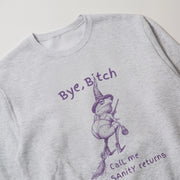 A grey sweatshirt with a purple illustration of a frog wearing a witch's hat and holding a broom, along with the text 