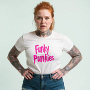 A woman with red hair and tattoos is wearing a white t-shirt with the text 