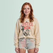 A young woman with red hair wearing a beige sweatshirt with the text 