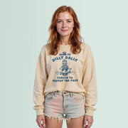 A young woman with red hair wearing a beige sweatshirt with a graphic design and text, standing against a light blue background.