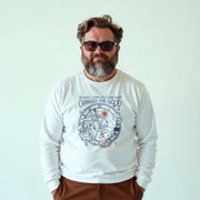 A man with a beard wearing a white long-sleeved shirt with a graphic design and text printed on it.