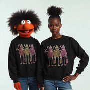A person wearing a black sweater with a group of cartoon-like figures and a large, colorful character on it, posing with another person.