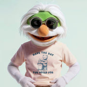 A person wearing a pink t-shirt with a graphic and text, smiling and wearing sunglasses.