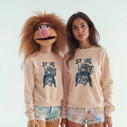 Two women wearing matching light pink sweatshirts with a cartoon character printed on them, posing together.