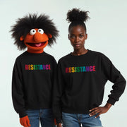 two people, one wearing a colorful Muppet-style character costume and the other wearing a black sweatshirt with the word 
