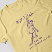 A yellow t-shirt with a graphic design depicting a frog wearing a witch's hat and holding a broom, along with the text 