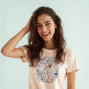 A smiling woman with long brown hair wearing a white t-shirt with a graphic design.