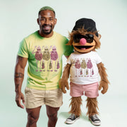 A man in a yellow t-shirt and khaki shorts stands next to a large, furry mascot wearing a white t-shirt, pink shorts, and a black hat.