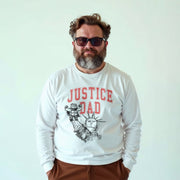 A man with a beard wearing a white long-sleeved shirt with a graphic design and text printed on it.
