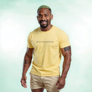 A smiling man with a beard wearing a yellow t-shirt with the text 