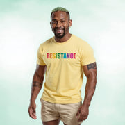 A smiling man wearing a yellow t-shirt with the word 