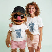 A woman wearing a white t-shirt with a bunny graphic and pink shorts stands next to a large stuffed animal wearing a black hat and sunglasses.