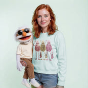 A woman with red hair is holding a large, colorful, cartoonish character in front of her.
