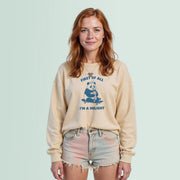 A young woman with red hair wearing a beige sweatshirt with a graphic of a panda and the text 