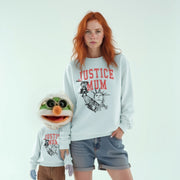 A woman with red hair wearing a white sweatshirt with the text 