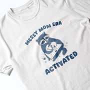 A white t-shirt with a graphic design featuring a raccoon holding a baby and the text 