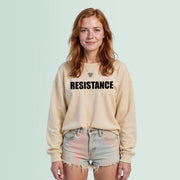 A young woman with red hair wearing a beige sweater with the word 