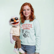 A woman with red hair is holding a large stuffed animal, which appears to be a character from a television show or movie. The woman is wearing a light blue sweatshirt with the text 