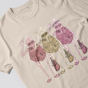 A t-shirt with a graphic design featuring three stylized women in colorful outfits, each holding a different object such as a purse, umbrella, and a cup.