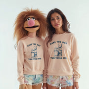 Two women wearing matching light pink sweatshirts with a cartoon character and text printed on them.