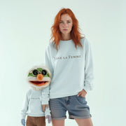 A woman with red hair wearing a white sweatshirt with the text 