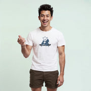 A smiling man wearing a white t-shirt with a graphic of a panda on it, standing against a light blue background.