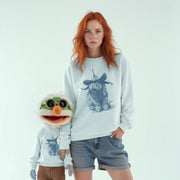 A woman with red hair wearing a white sweatshirt with a graphic of a rabbit and a clown face stands next to a smaller stuffed rabbit wearing a clown face.