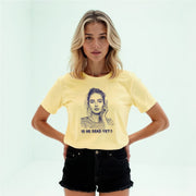 A young woman with blonde hair wearing a yellow t-shirt with a graphic design and text printed on it.