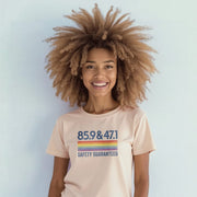 A smiling woman with curly hair wearing a light pink t-shirt with a graphic design.