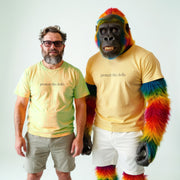 A man in a yellow t-shirt and sunglasses stands next to a gorilla with colorful fur, both wearing matching yellow t-shirts with the text 