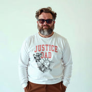 A man with a beard wearing a white long-sleeved shirt with a graphic design and text printed on it.