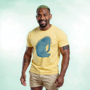 A smiling man wearing a yellow t-shirt with a blue elephant graphic and khaki shorts.