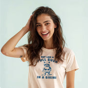 A smiling woman with long brown hair wearing a white t-shirt with a graphic and text printed on it.