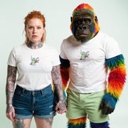 A woman with red hair and tattoos is standing next to a gorilla with colorful fur, both wearing white t-shirts with a graphic design.