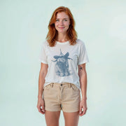 A woman with red hair wearing a white t-shirt with a graphic of a rabbit and khaki shorts, smiling at the camera.