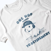 A white t-shirt with a graphic design featuring a cartoon rabbit wearing a baseball cap and the text 